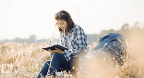 Woman writing in a journal while sitting in a field