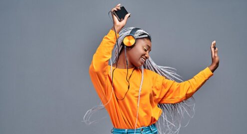 Student in bright orange shirt dances to the playlist she created in class.