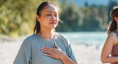 A middle-aged Asian educator practices self-compassion outside